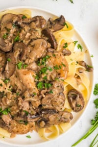 plate of chicken marsala on wide noodles.