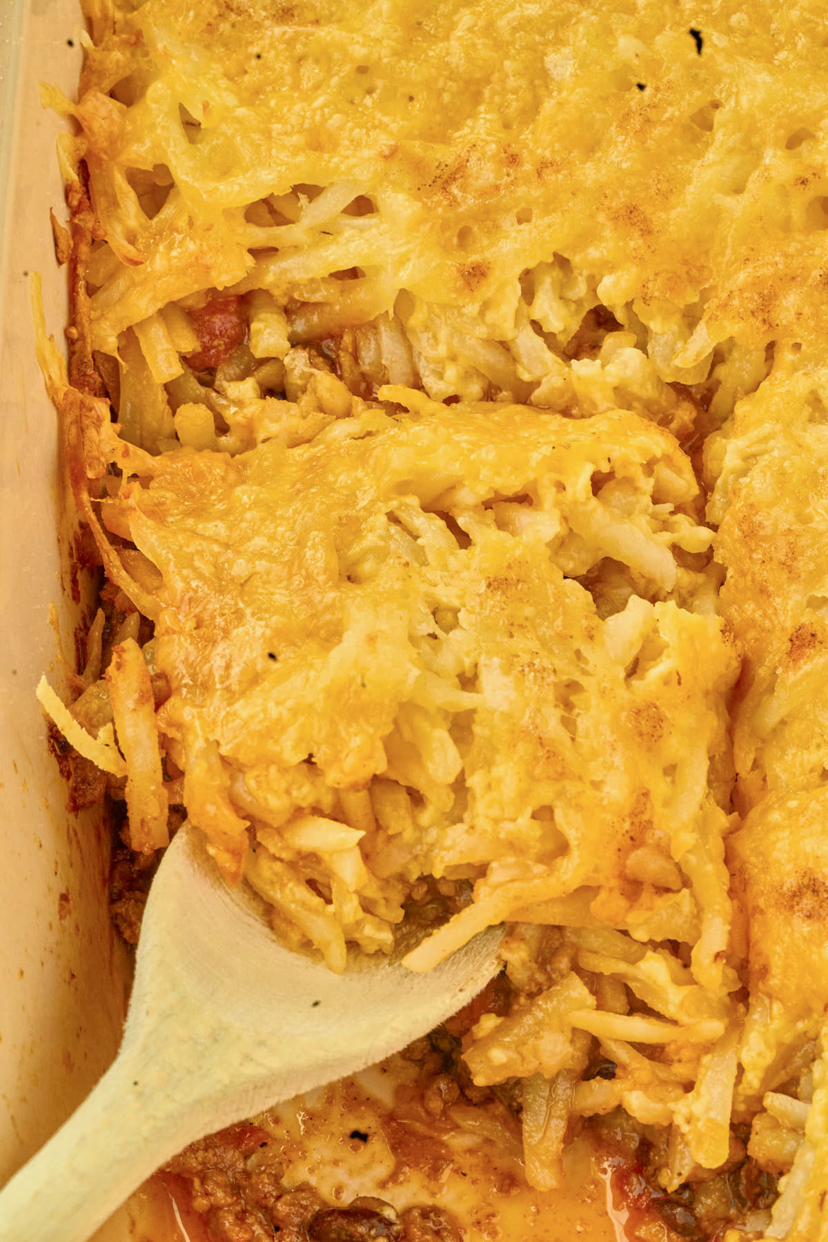 wooden spoon portioning out slice of casserole.