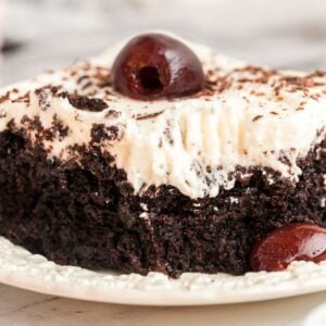 close up view of chocolate cake with cherries and creamy frosting.