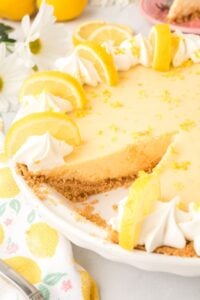 lemon pie garnished with whipped cream and lemon, slice missing.