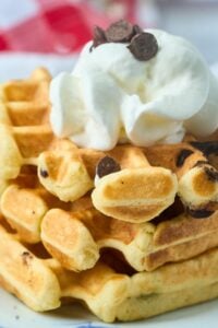 plate of sourdough chocolate chip waffles topped with whipped cream.