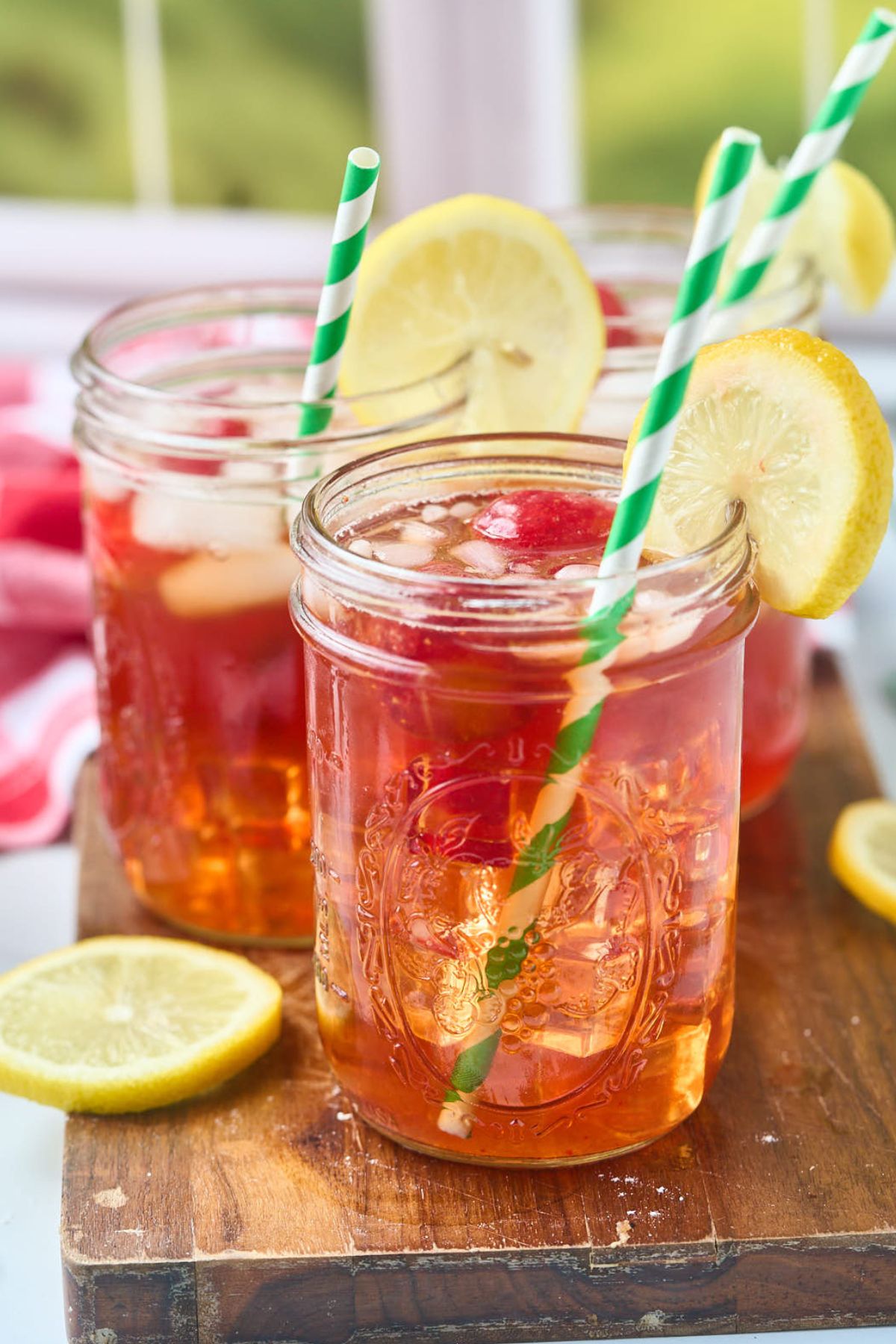3 glasses of strawberry iced tea in front of window.