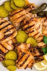grilled chicken on plate with pickles and garnish.