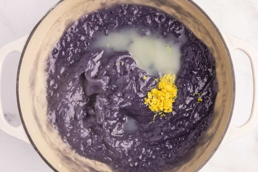 Thick purple mixture in a pot topped with yellow lemon zest.
