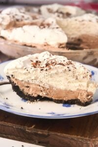 slice of ice cream pie with oreo crust on blue and white plate.