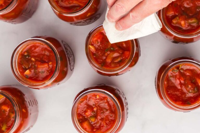 wiping off mason jars of salsa.