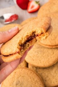 sandwich cookie with jam bite missing.