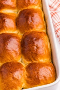 Freshly baked soft sourdough dinner rolls in a baking dish, golden brown and fluffy.