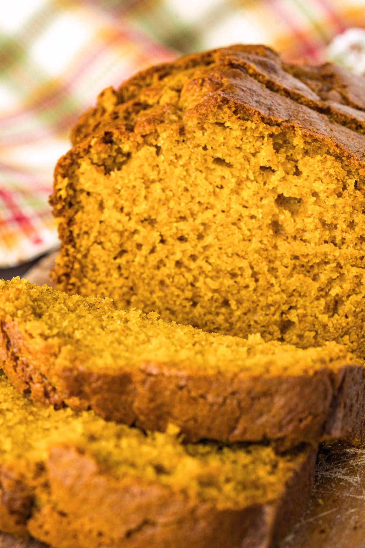 a baked loaf of sourdough pumpkin bread on a cutting board, with a few slices cut.