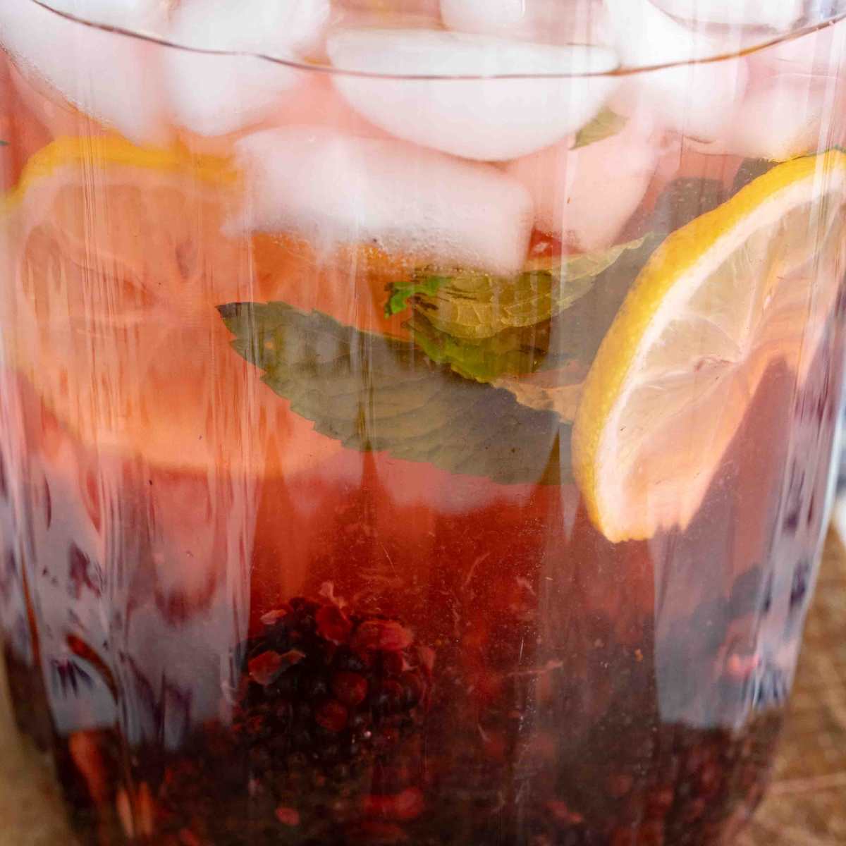 close up of pitcher of blackberry lemon water wth fruit and ice cubes.