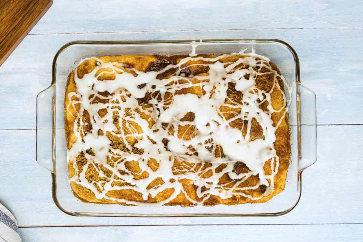 A coffee cake with a white glaze in a glass baking dish.