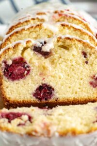Sliced blackberry lemon pound cake arranged in a staggered line, showcasing the moist crumb and berry distribution, with a crisp white glaze on top.