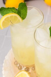 glass of lemonade filled with ice and garnished with lemon slice and mint leaves.