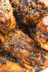 Close-up of crispy Cajun-seasoned chicken wings on a plate, showcasing the spices clinging to the fried, golden-brown skin.