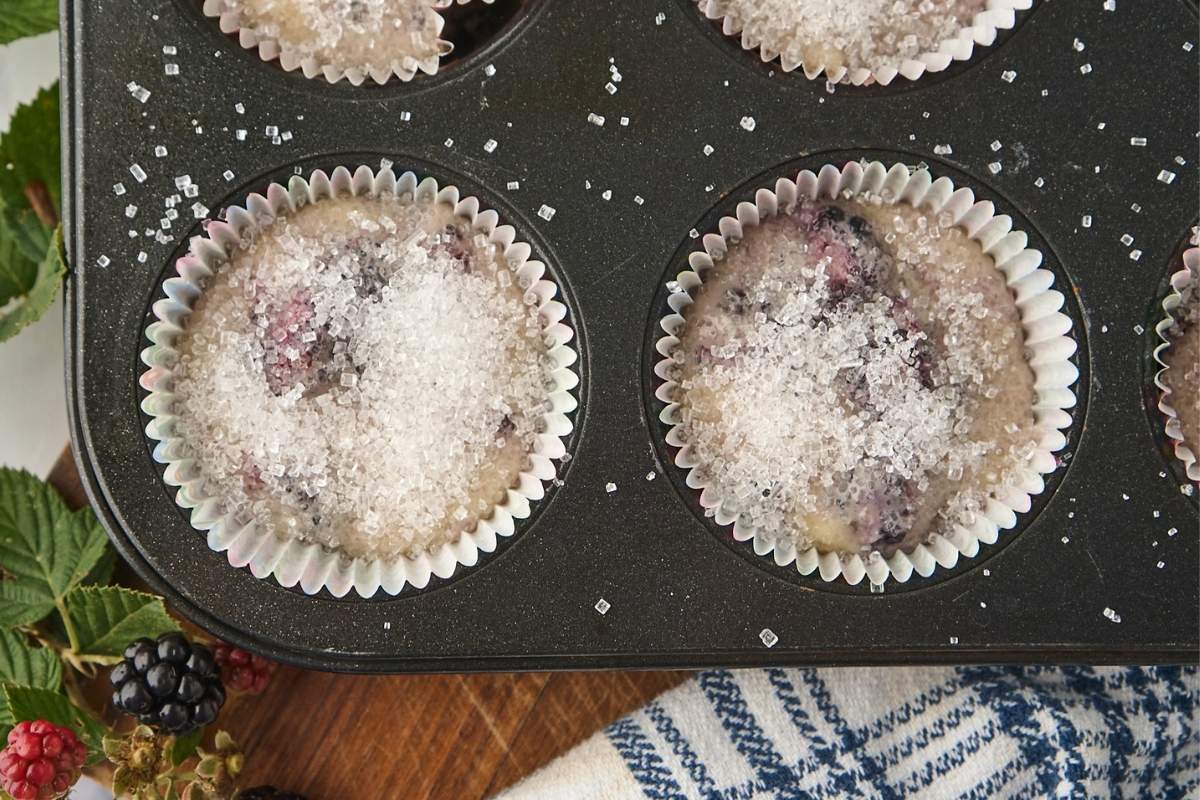 batter in muffin tin with sugar on top.