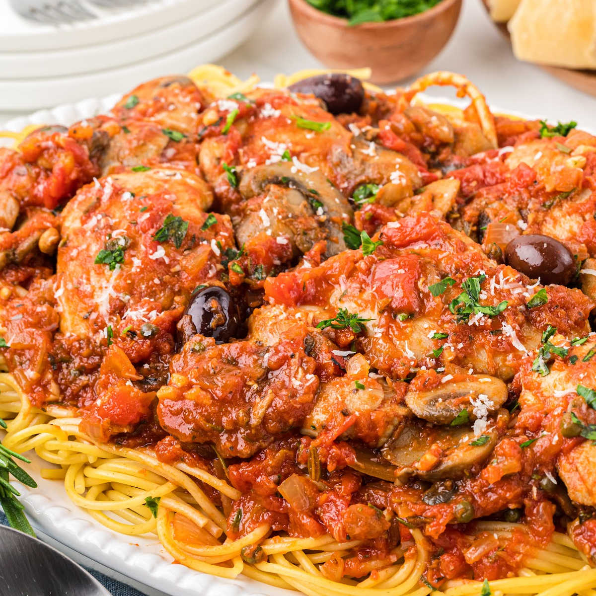 plate of chicken cacciatore served over spaghetti noodles.