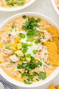 A bowl of White Chicken Chili topped with a generous amount of shredded cheese and cilantro, highlighting the dish's creamy consistency and fresh toppings.