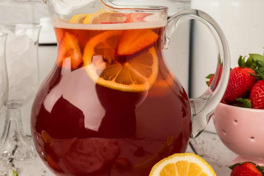 pitcher of strawberry sweet tea with lemon slices inside.