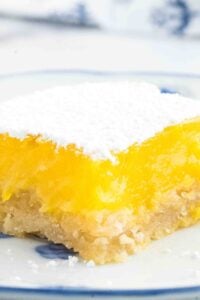 Close-up of a sourdough lemon bar, giving a clear view of the dusting of powdered sugar that adds a delicate sweetness to the tangy lemon topping and textured crust