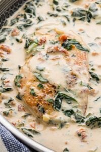 Close-up of a Tuscan chicken breast in a creamy garlic and Parmesan sauce with spinach and sun-dried tomatoes.
