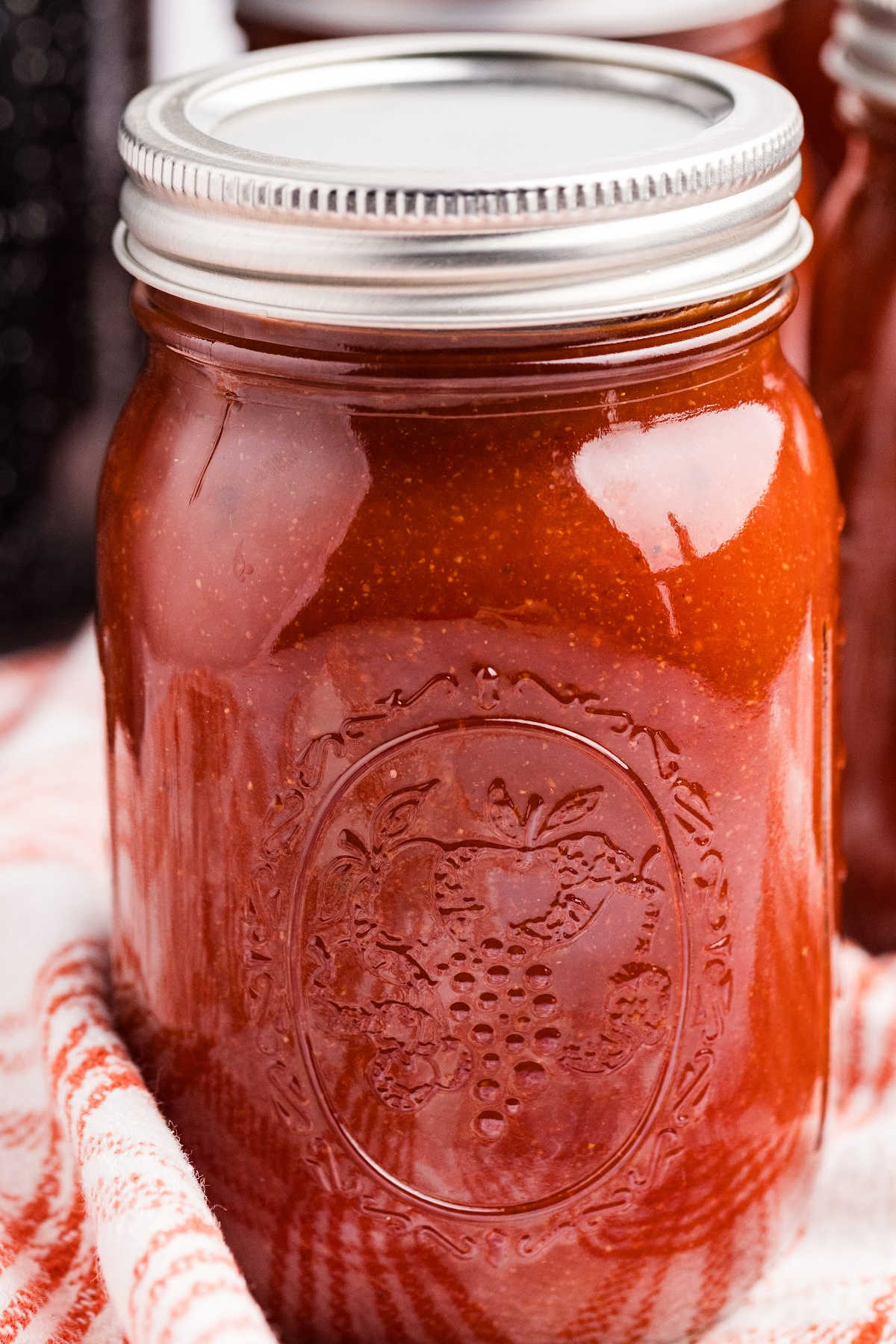 sealed jar of barbecue sauce on wooden board.