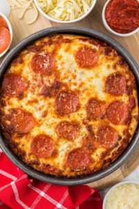 Pizza Ingredients Layout. An overhead view of pizza ingredients neatly arranged on a marble countertop, including bowls of flour, yeast, olive oil, milk powder, cheese, pepperoni, and spices.