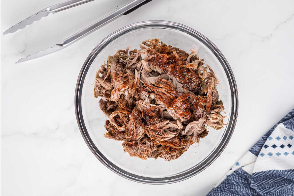 shredded pork with spices in glass bowl.