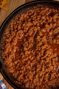 Close-up view of ground beef chili simmering in a cast iron skillet.
