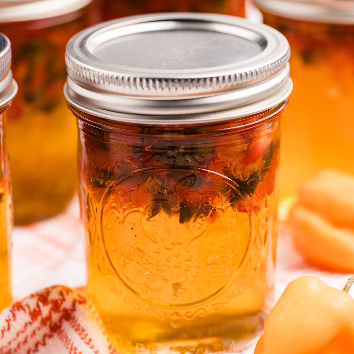 sealed jar of hot pepper jelly with peppers floating on the top.