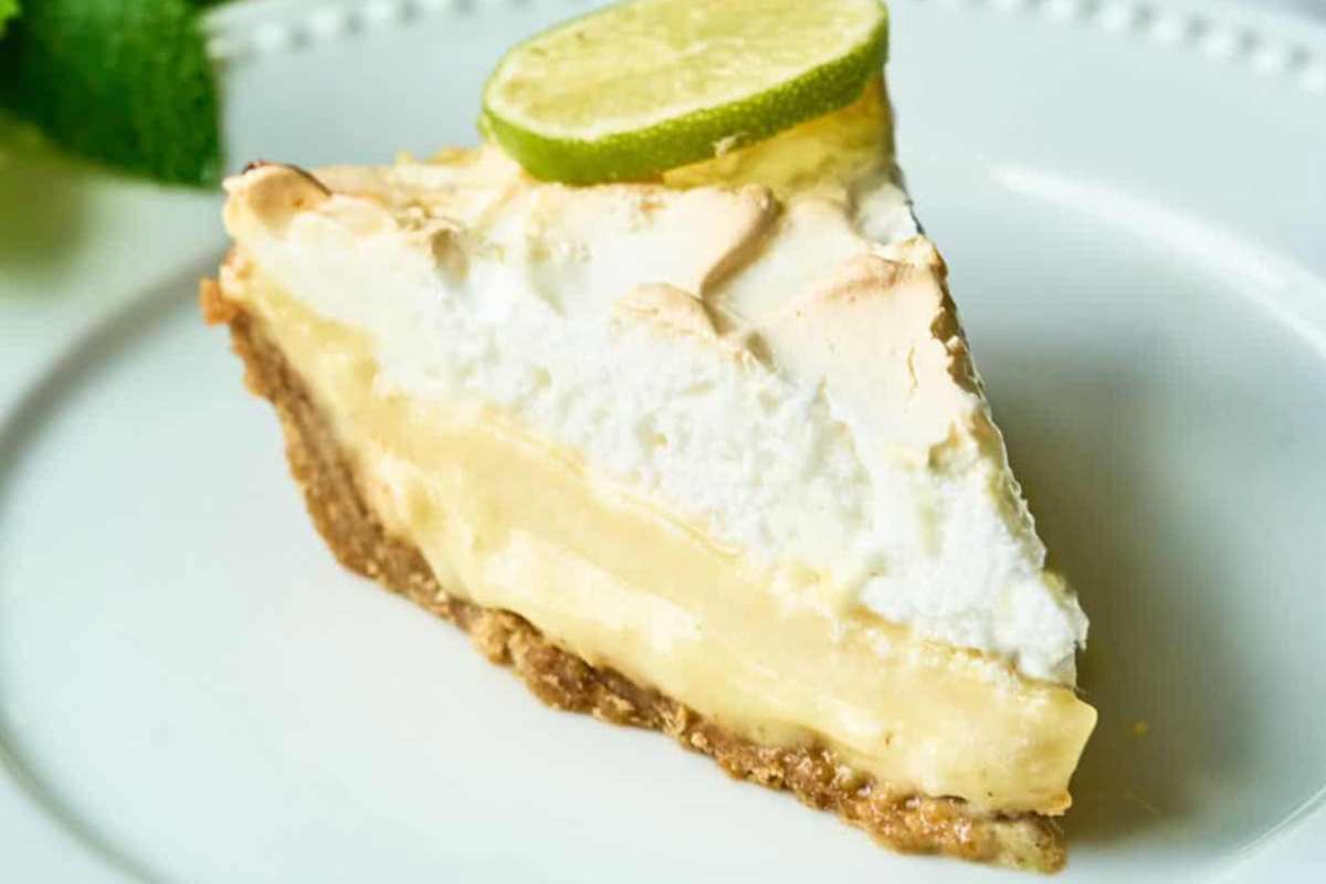 slice of key lime pie with a meringue topping on a white plate.