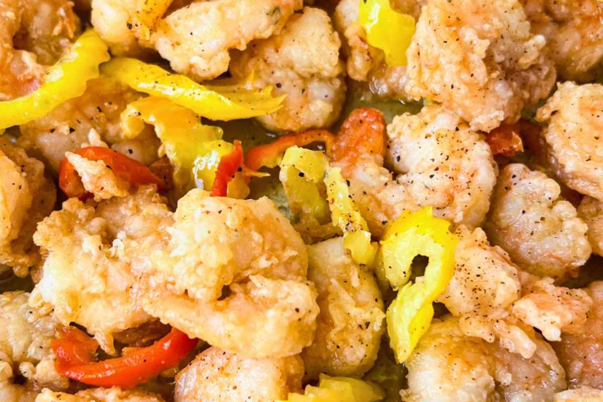 close-up of fried shrimp mixed with sliced yellow and red peppers.