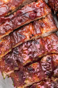Close-up shot of sliced baby back ribs coated in a rich, glossy barbecue sauce, showcasing the tender, juicy meat.