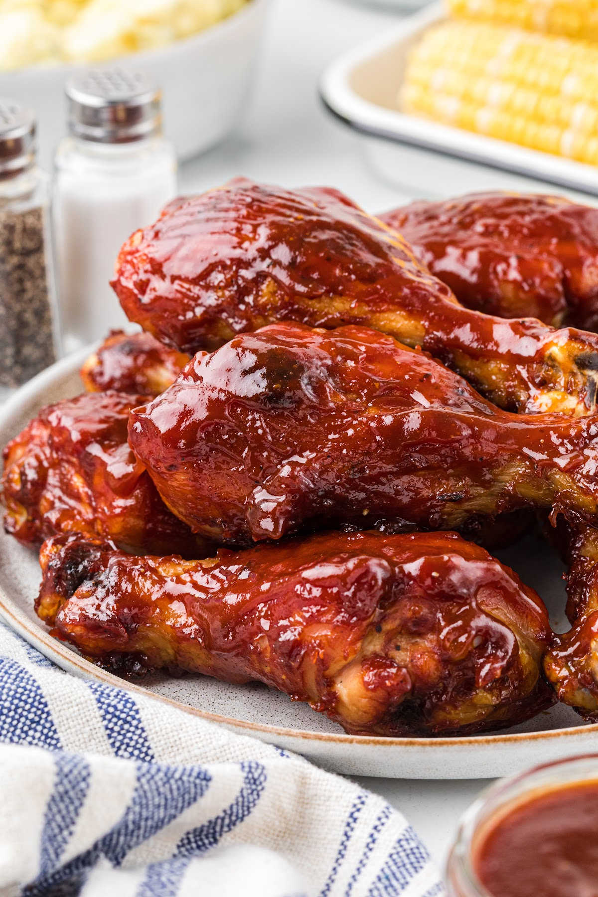 plate of chicken drumsticks covered in barbecue sauce.