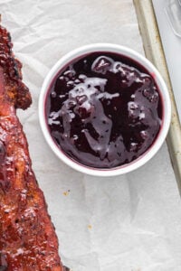 overhead view of dark purple homemade bbq sauce in white dish.