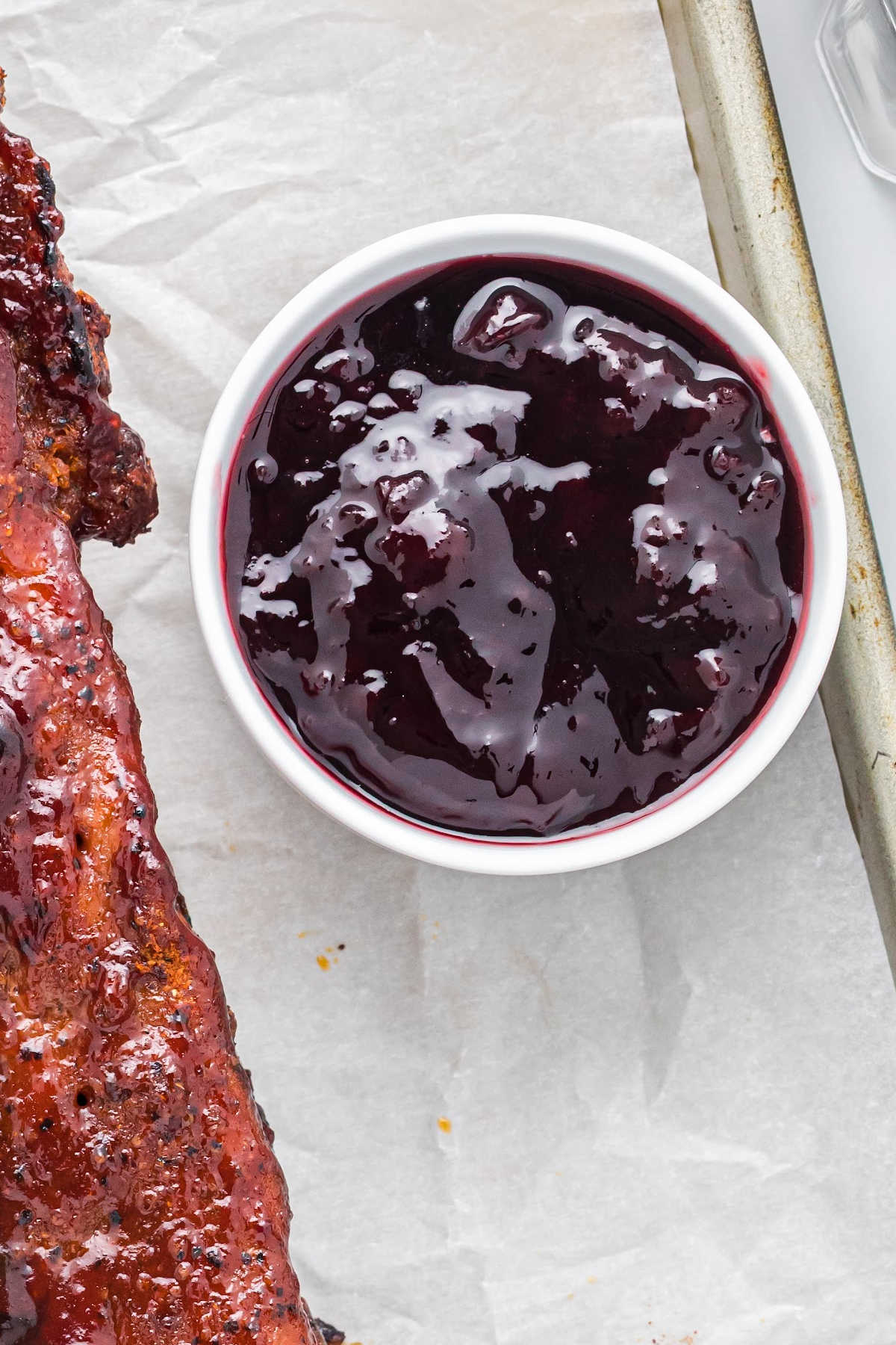 overhead view of dark purple homemade bbq sauce in white dish.