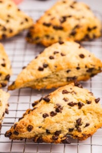 Close-up of golden-brown sourdough scones with chocolate chips on a cooling rack.