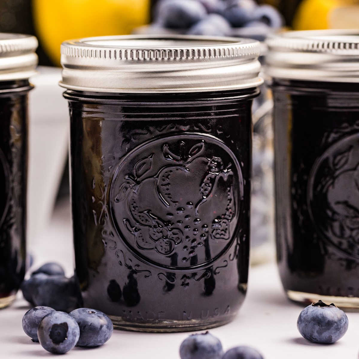 jars of blueberry preserves with blueberries in front.