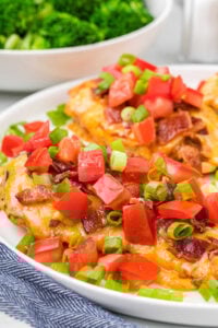 Monterey Chicken served on a white plate with a side of steamed broccoli, garnished with fresh diced tomatoes and green onions.