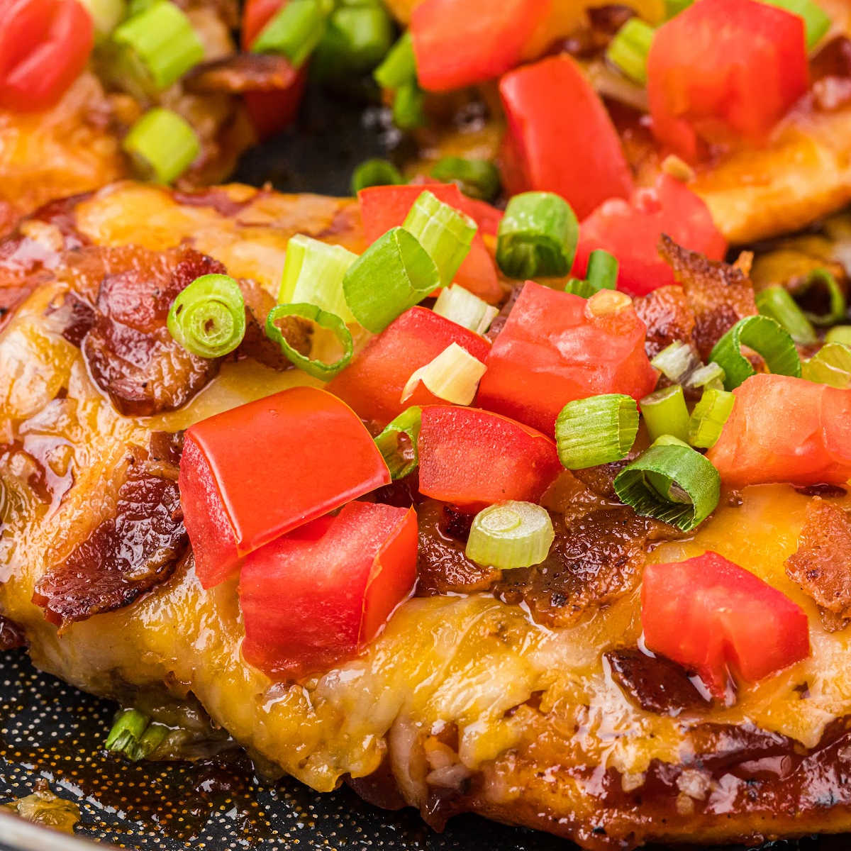 close-up of Monterey Chicken, topped with bacon, cheese, diced tomatoes, and green onions.