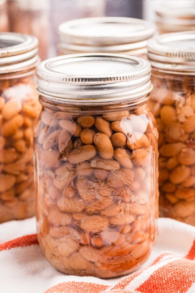 Close-up of a mason jar filled with pressure canned pinto beans with additional jars in the background.