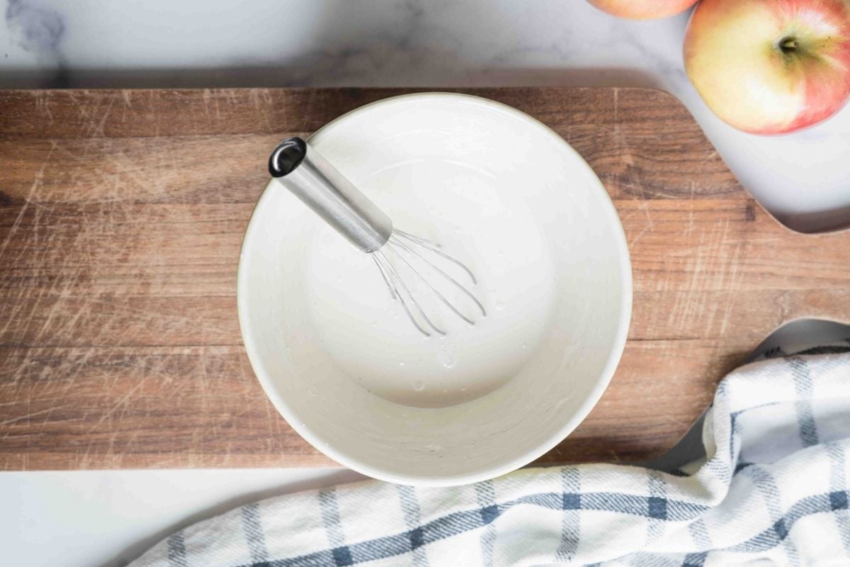 small white bowl with glaze and whisk.