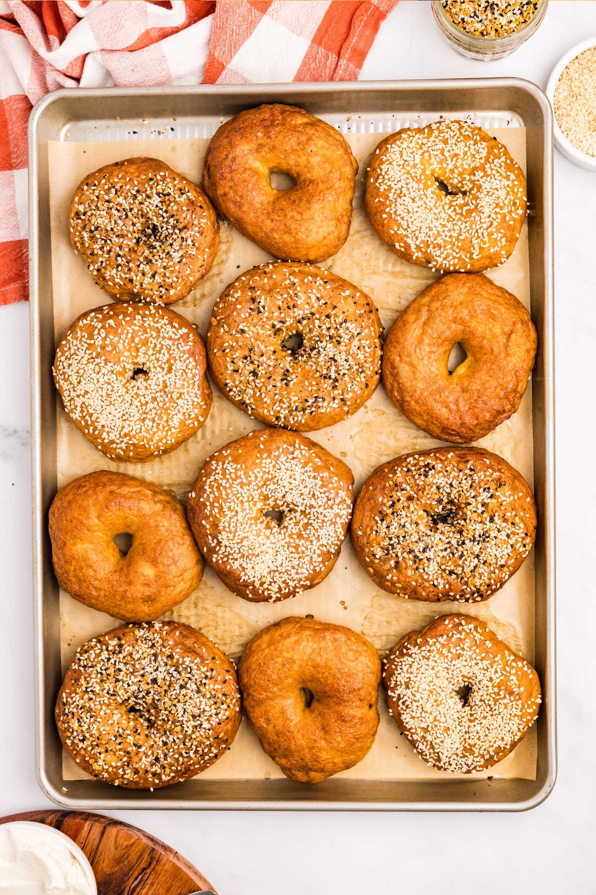 overhead view of sourdough bagels on baking sheet.