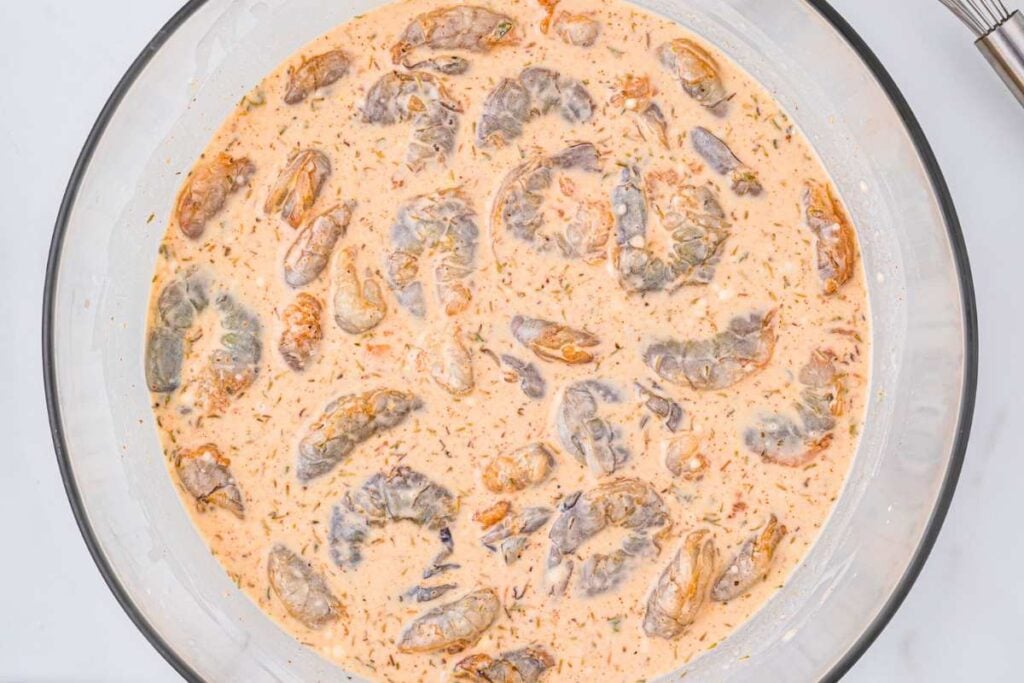shrimp soaking in a seasoned batter mixture.