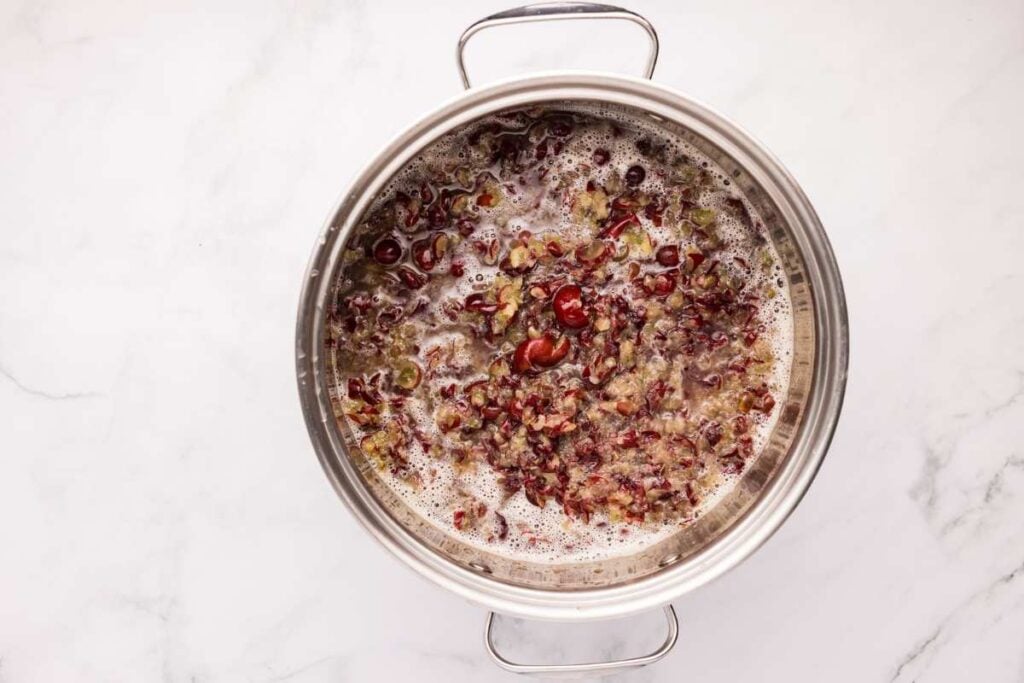 A pot of simmering mashed grapes, showing the mixture bubbling as it cooks.
