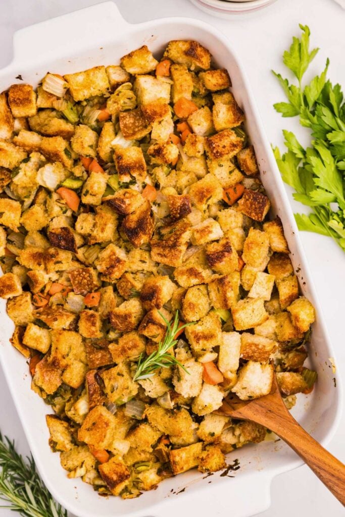 sourdough stuffing in casserole dish with wooden spoon.