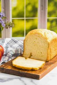 front shot of bread with one slice cut on counter in front of window.