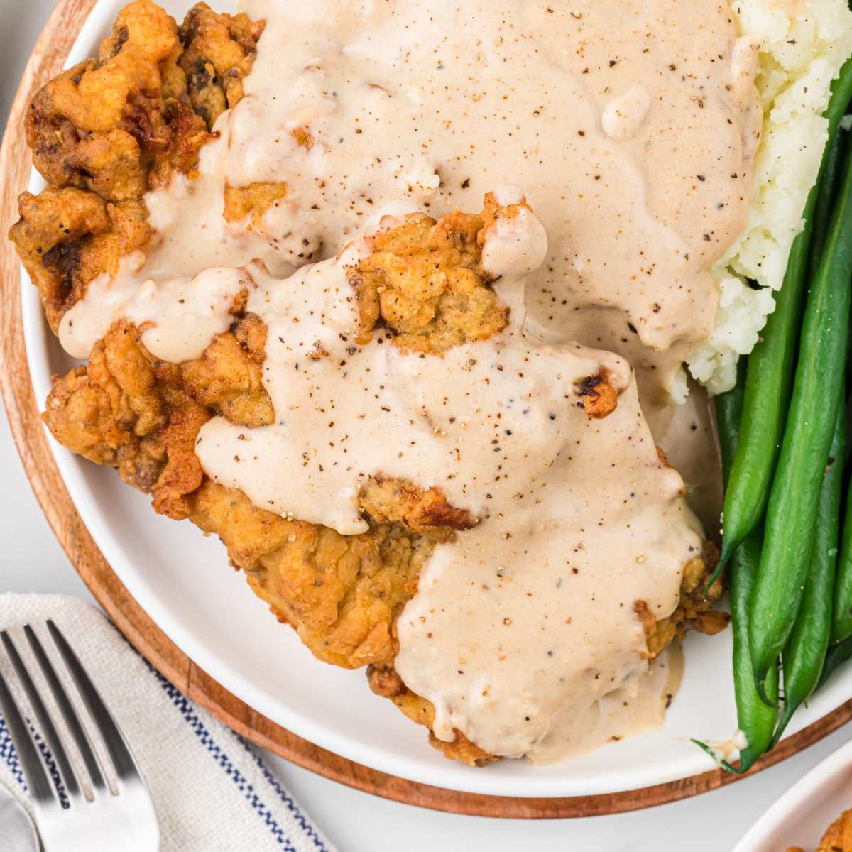 overhead view of fried steak with gravy on plate.