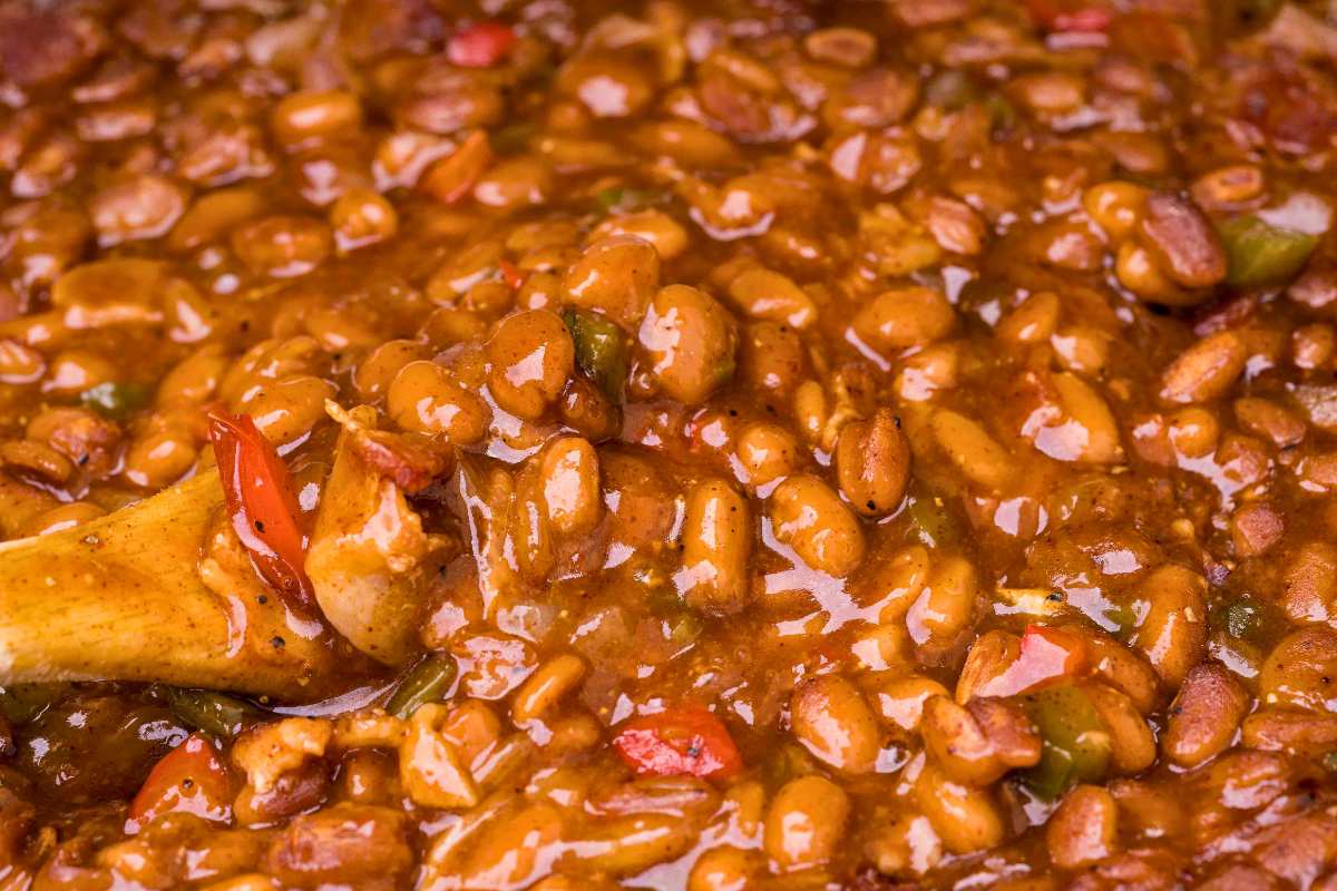 close up shot of beans with a wooden spoon in it.