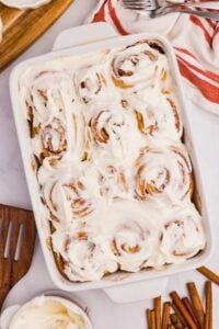 overhead shot of frosted cinnamon rolls in pan on counter.