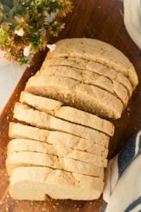 overhead of french bread sliced up on wooden cutting board.